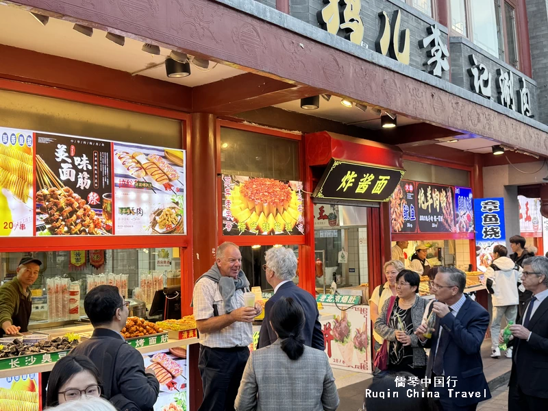 Foreign travellers tasting street food in Yandai Xiejie, Beijin