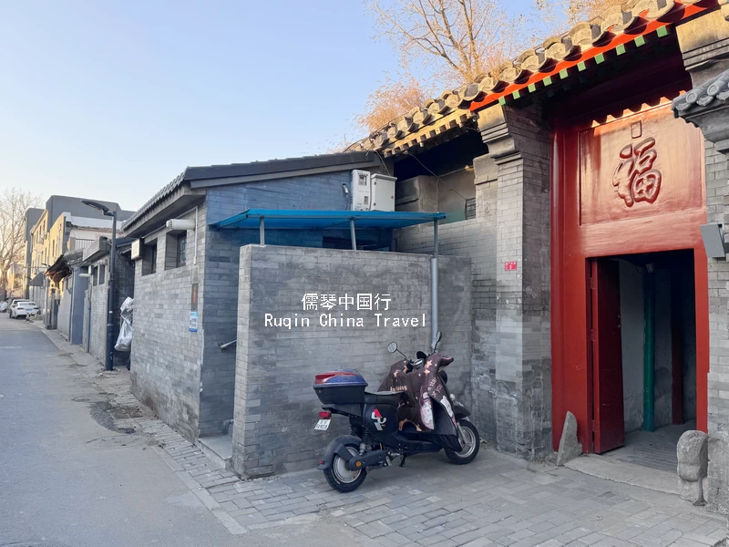 The intricate carvings on the eaves and the red wooden gate at Caochang Toutiao Alley