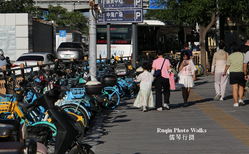 rows of shared bicycles neatly lined up at intervals along Jianguomen wai Dajie sidewalk