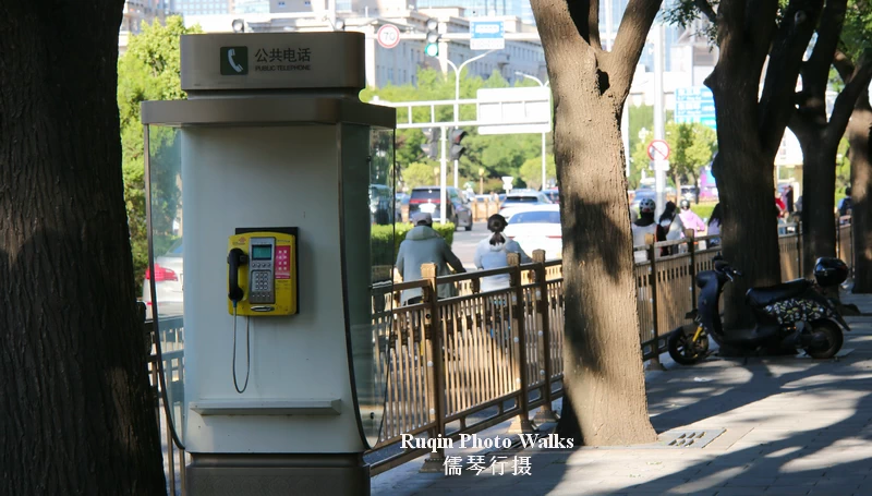 an old public telephone booth standing by the roadside at Jianguomenwai Dajie