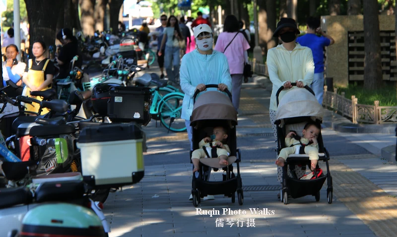 two young mothers walked side by side, each pushing a stroller at Jianguomen Outer  Avenue