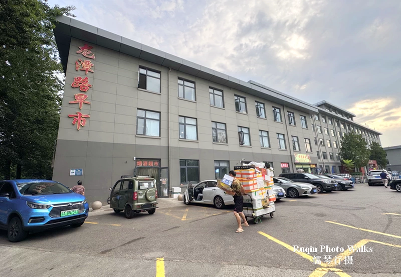 The main north entrance to Longtan Road Morning Market and its parking area.