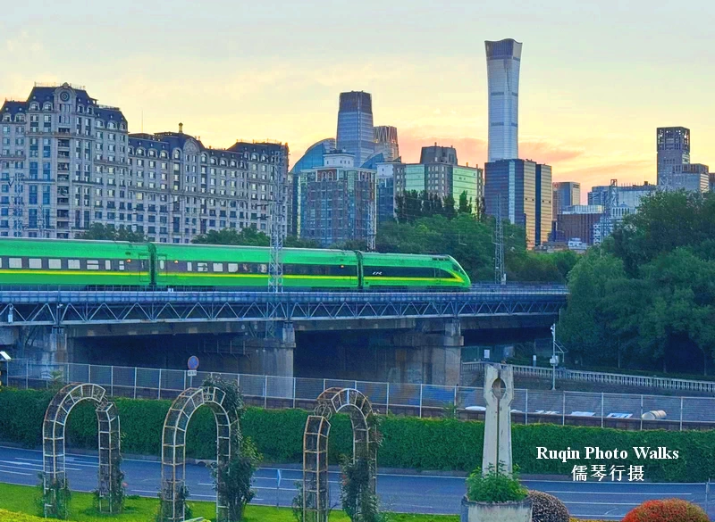 The prominent China Zun Tower and the sleek green Fuxing high-speed train seen from my Beijing Ming City Wall Relics Park Morning Walk
