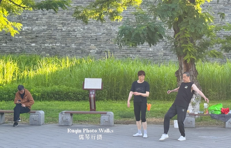 A couple are playing jianzi (Chinese shuttlecock) by the wall as part of their morning exercise routine in Beijing Ming Dynasty Wall Relics Park