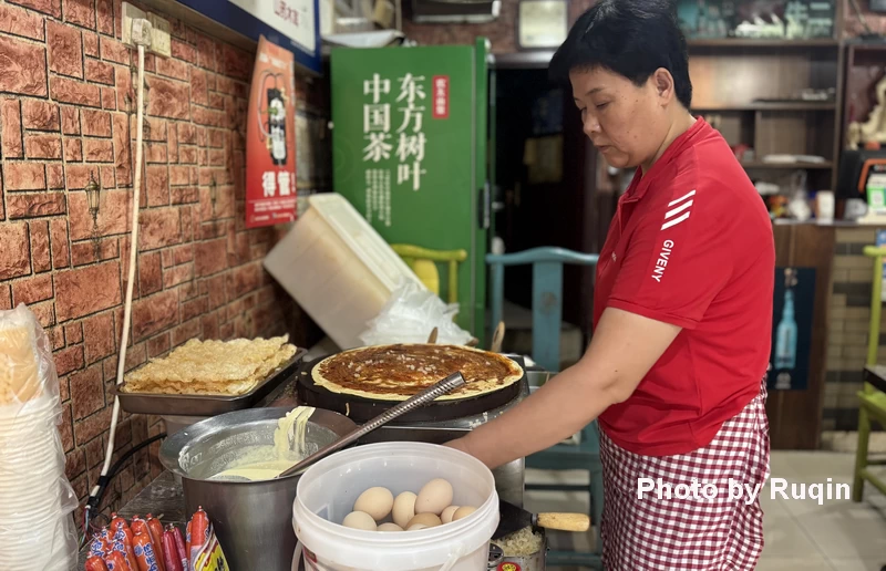 A woman preparing jianbing, a traditional Chinese breakfast pancake.