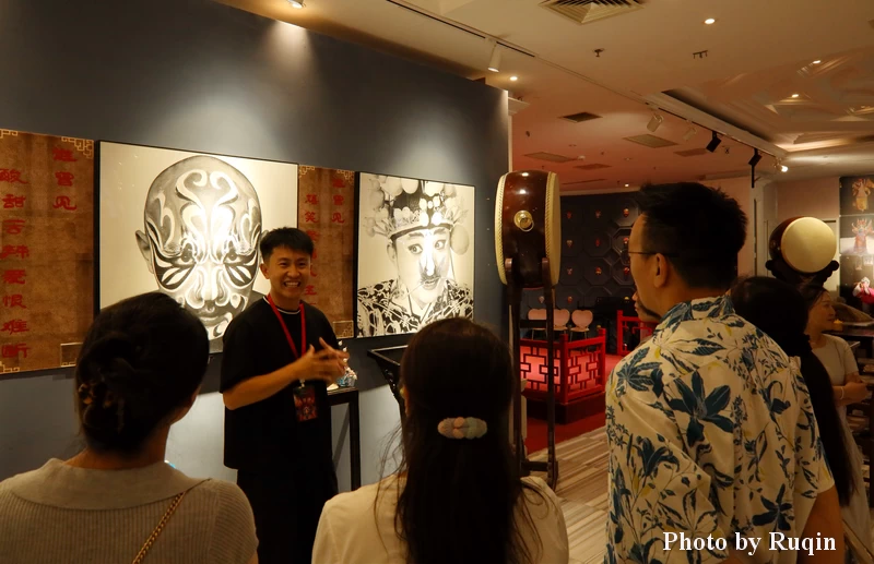A young staff member explaining Peking Opera roles at Tianle Theatre